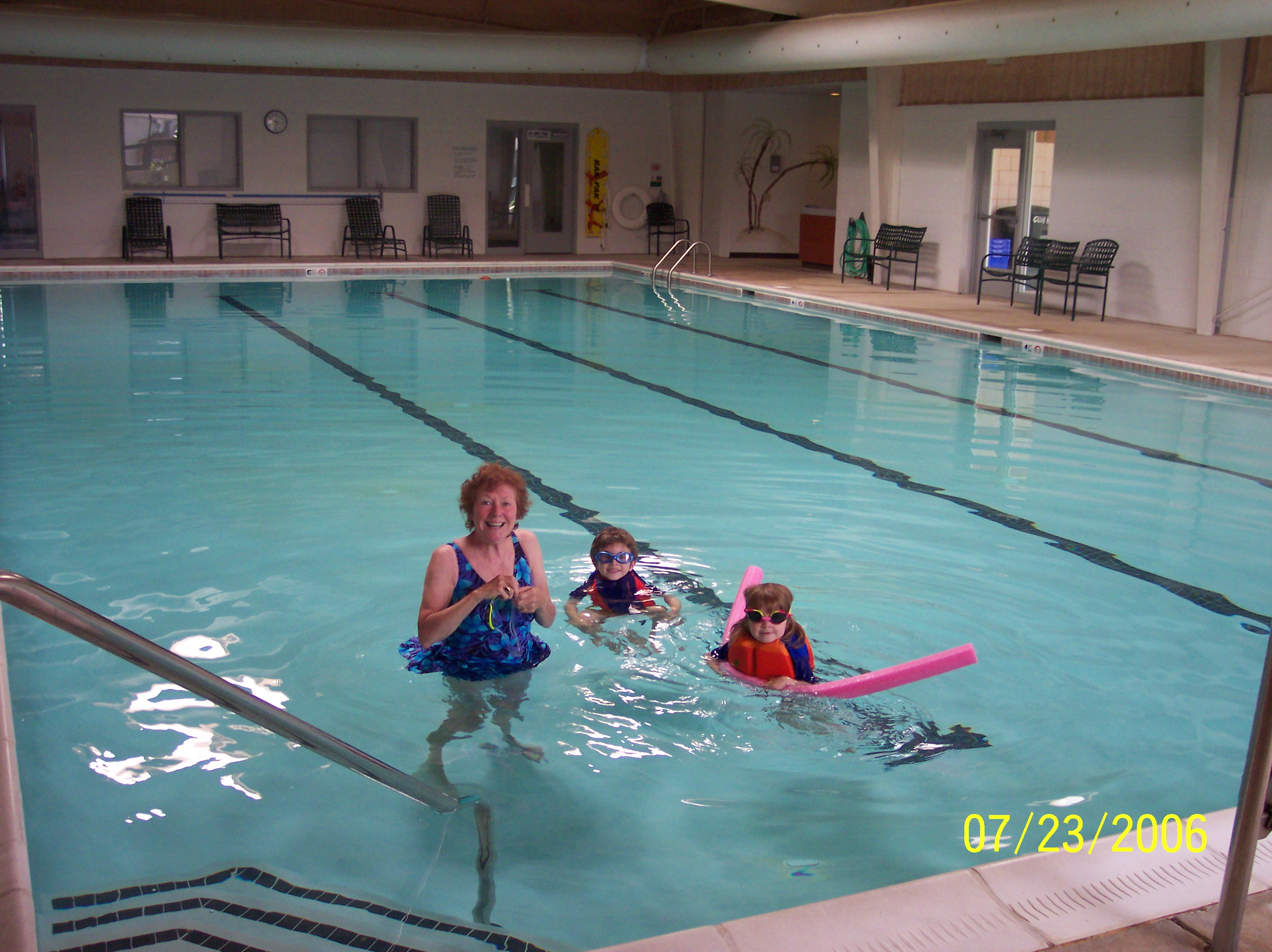 A woman and two children play together in a swimming pool